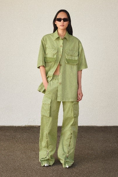 穿着绿色衣服的人站在墙边 描述已自动生成