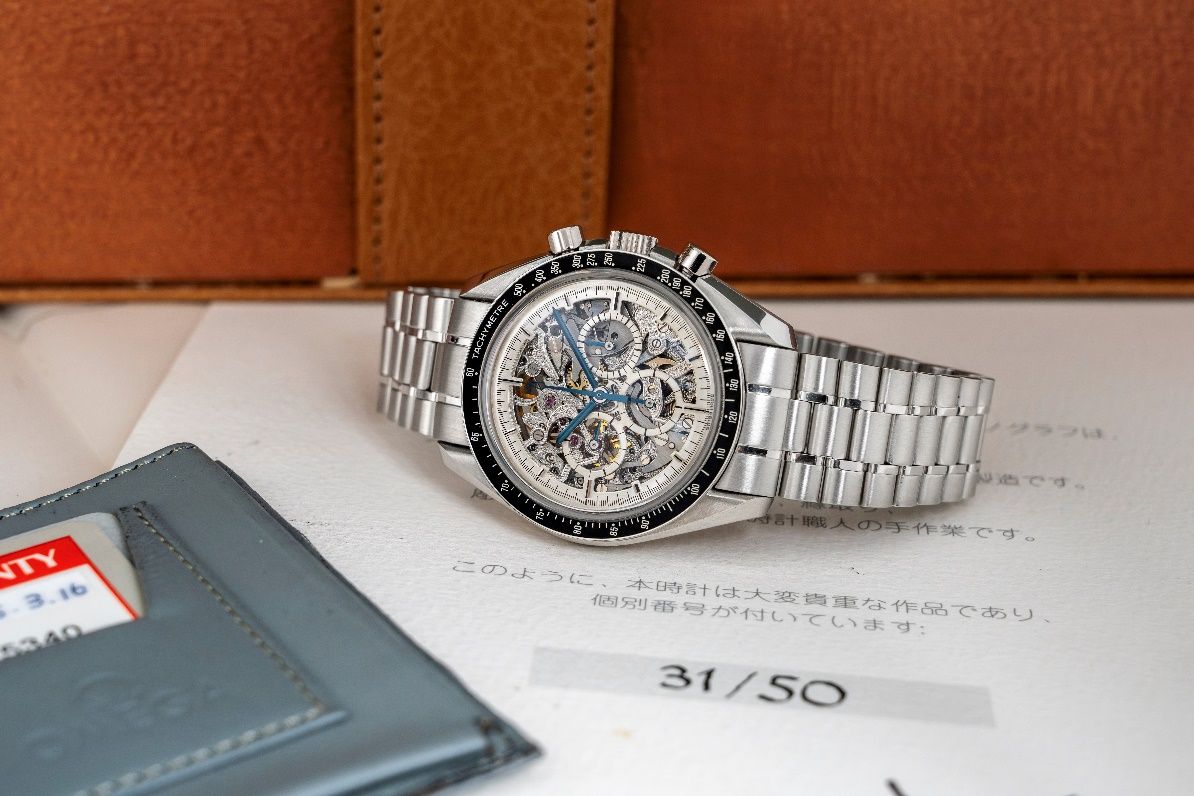 A silver watch on a piece of paper Description automatically generated
