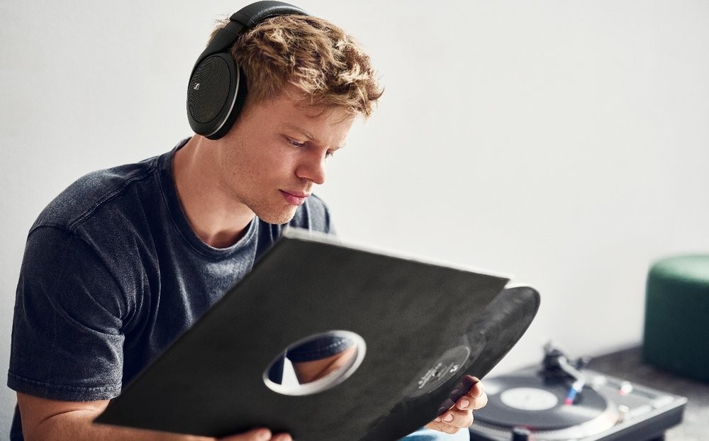 A person wearing headphones looking at a record
Description automatically generated