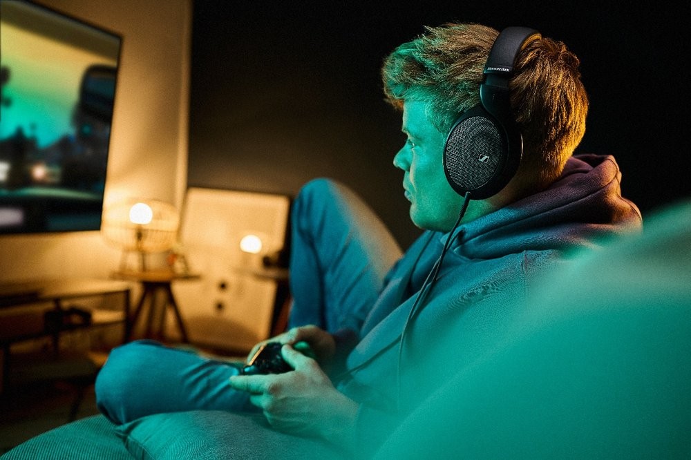 A person wearing headphones and holding a game controller
Description automatically generated